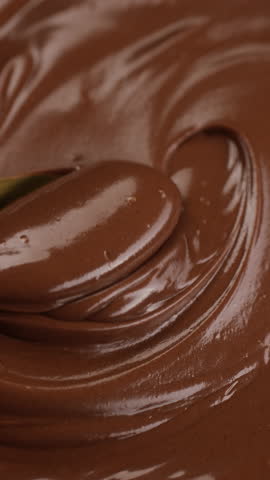 Stirring melted chocolate with golden spoon, close up. Liquid chocolate swirl