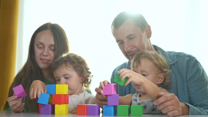 Family play constructor game with blocks. Brother sister building colorful block tower. Parents guide Brother sister fun constructor game. Family bonding blocks. Siblings enjoy creative play together.