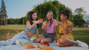 Asian, caucasian and african american women cheering with glasses of orange juice while having weekend brunch. Thirsty ladies enjoying refreshing liquid for resting from shining sun and laughing. - Powered by Shutterstock - Get 15% off with code: PIKWIZARD15