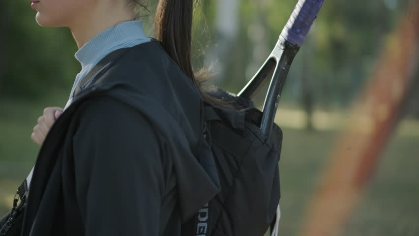 Female Tennis Player Walking with Gear Bag and Racket