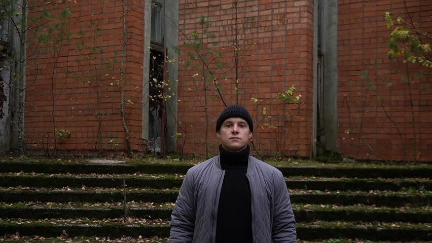portrait of a 20-year-old young man standing against the background of a ruined abandoned building. dark frightening atmosphere.