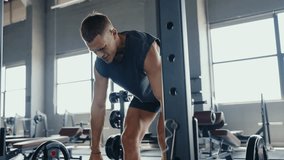 A focused man lifting weights in a contemporary gym setting, showcasing determination and physical strength during a workout session. Man Weightlifting in Modern Gym with Fitness Equipment - Powered by Shutterstock - Get 15% off with code: PIKWIZARD15