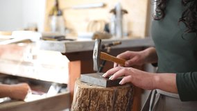 A skilled female jeweler hammers a ring into shape, showcasing her craftsmanship in a bright workshop. The focus is on the intricate process and attention to detail in jewelry making. - Powered by Shutterstock - Get 15% off with code: PIKWIZARD15