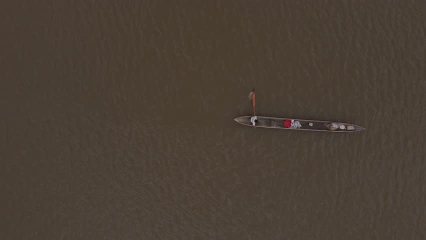 Aerial close-up view of a poler silhouetted rowing a Congo traditional canoe on the waterways of the Congo river