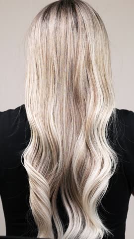 Vertical slow motion video of unrecognizable model with long blond straight hair