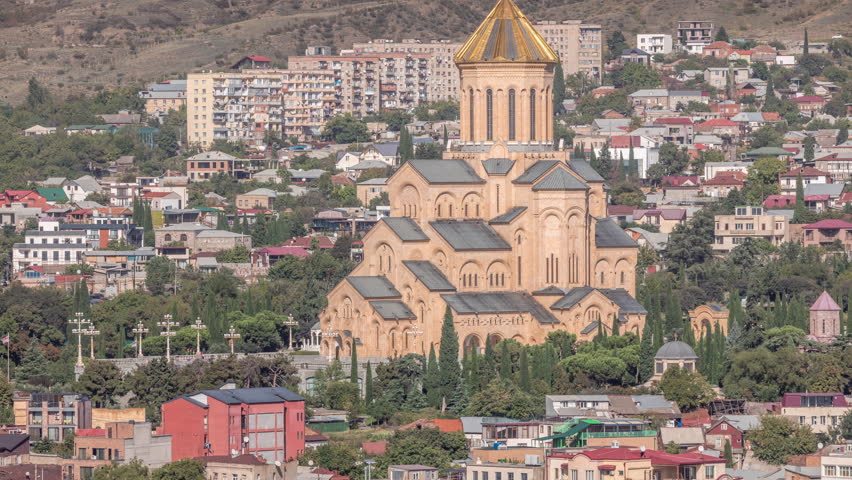 Tsminda Sameba Cathedral or Holy Trinity Cathedral of Tbilisi aerial timelapse. The main cathedral of the Georgian Orthodox Church in Tbilisi, Georgia. Houses on a background