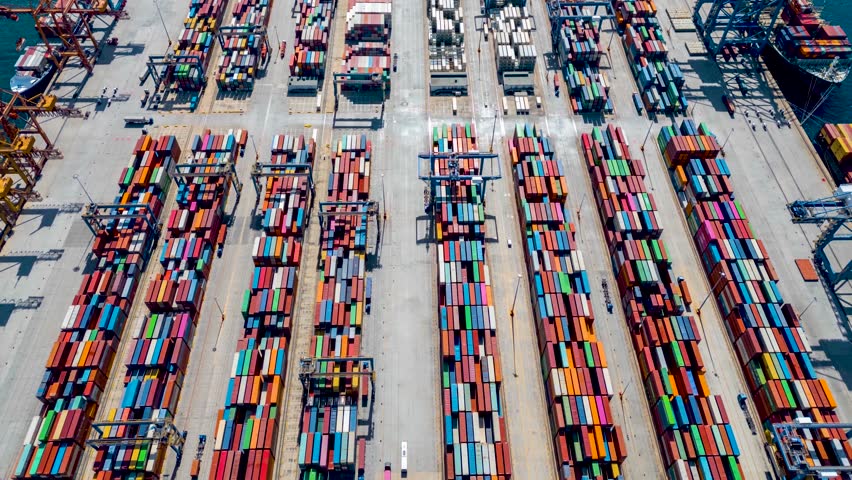 Aerial hyper lapse view of a industrial cargo container port with loading and unloading activity of ships by trucks and cranes