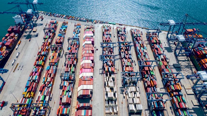 Aerial hyper lapse view of a industrial cargo container port with loading and unloading activity of ships by trucks and cranes - Powered by Shutterstock - Get 15% off with code: PIKWIZARD15