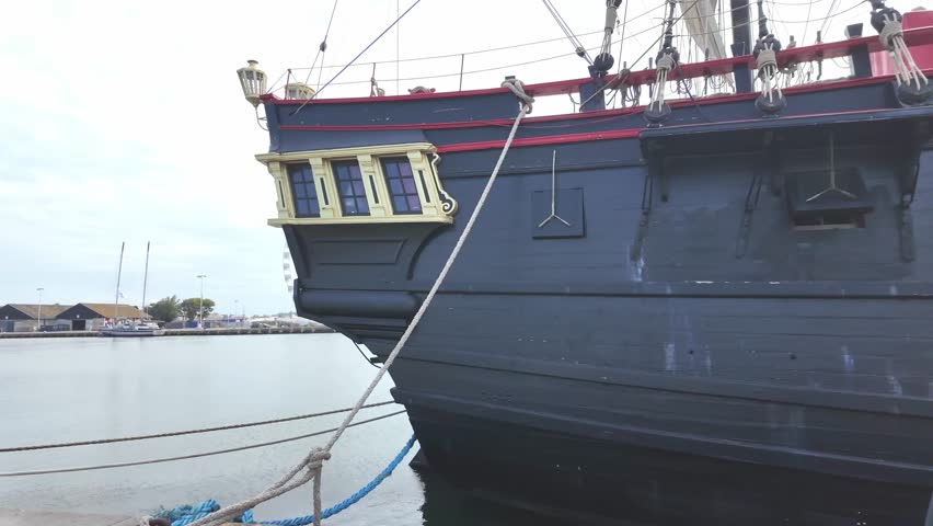Rear end of wooden black pirate ship, now tourist attraction and Ferris wheel in the distance, Saint Malo, France.