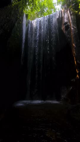 Vertical View of Tukad Cepung Waterfall, Bali Island, Indonesia. Water Flowing Into Cave in Tropical Jungle
