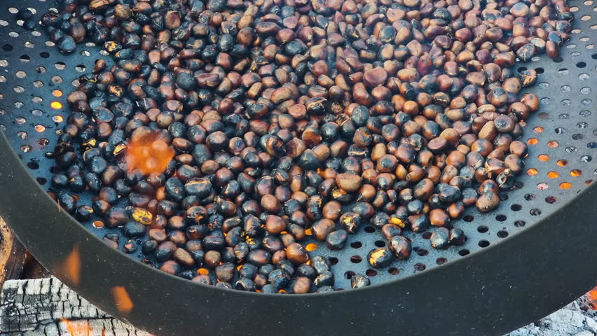   Roasting chestnuts on open fire in the street Portugal, popular autumn street food in Europe and Asia.