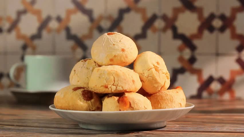 Pão de queijo. Traditional Brazilian cheese bread. pile with some cheese bread, Causasian woman takes a cheese bread from the pile. 