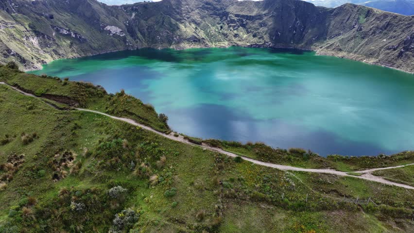 Quilotoa lake from volcano crater filled with water, Ecuador. Aerial drone lateral view and tilt-up