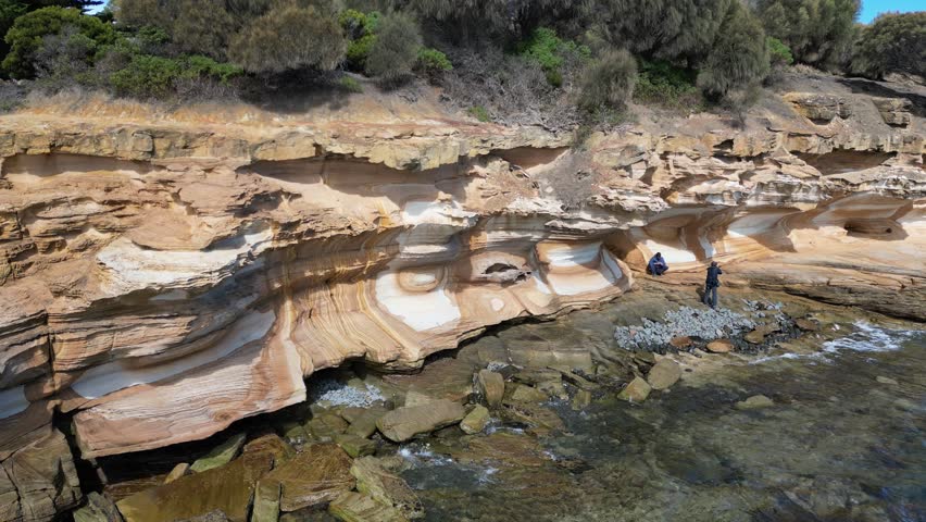 An ascending aerial footage of the scenic Painted Cliffs on Maria Island, on a sunny day in Tasmania, Australia
