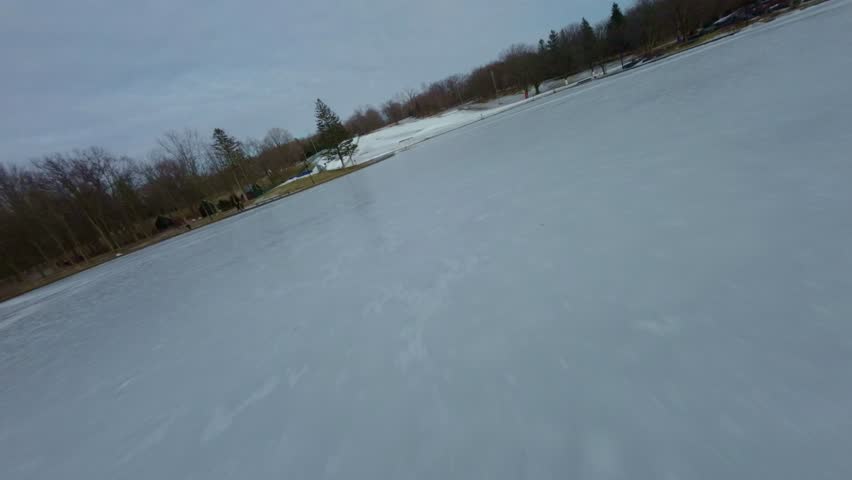 Ground-level FPV drone footage of Beaver Lake in Mount Royal during winter, Montreal