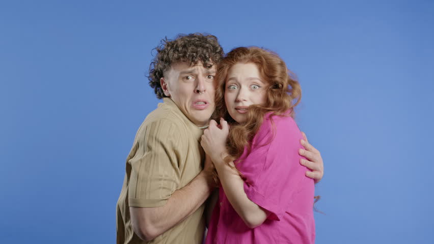 Frightened white american couple afraid of something. Man and woman in shock.