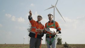 Renewable energy engineers working on wind turbine projects. Technician workers use a tablet to work together outdoors at windmill farms. Engineers research environmentally friendly ecology energy.  - Powered by Shutterstock - Get 15% off with code: PIKWIZARD15