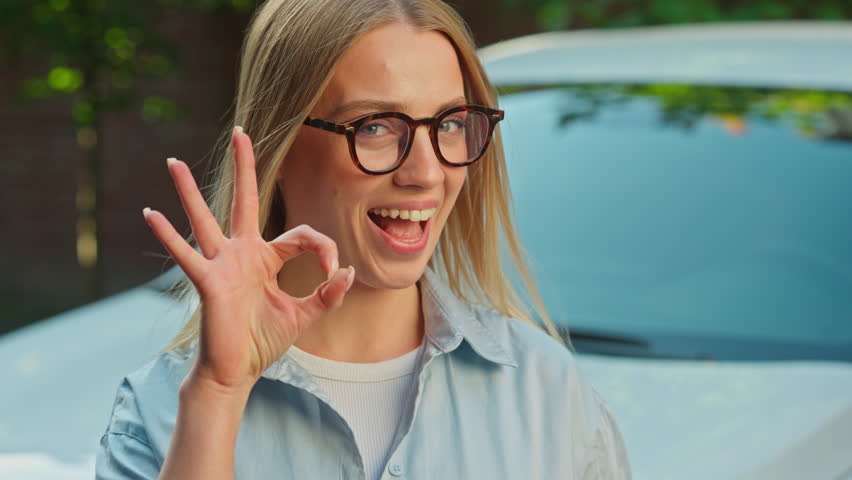 Happy Caucasian woman show okay like gesture good smile car auto girl female businesswoman test drive driver ok transport owner rent service positive hand sign approve alright yes recommend fingers