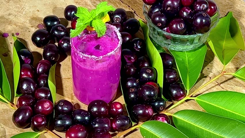 A glass full of jamun juice from a farm on a rotating table