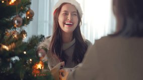 Excited asian woman wearing Santa hat getting surprise gift from her girlfriend at home. Gives a Christmas gift, birthday gift, New year day celebration and congratulation - Powered by Shutterstock - Get 15% off with code: PIKWIZARD15