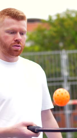 Portrait of a sportive man in pickelball court holding racket and ball