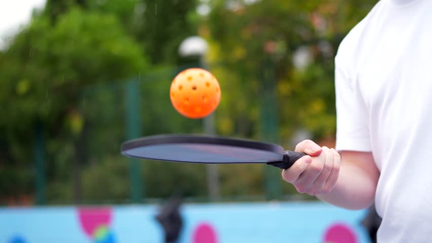 Low angle view portrait of a caucasian young man serving playing pickelball in an outdoor urban court