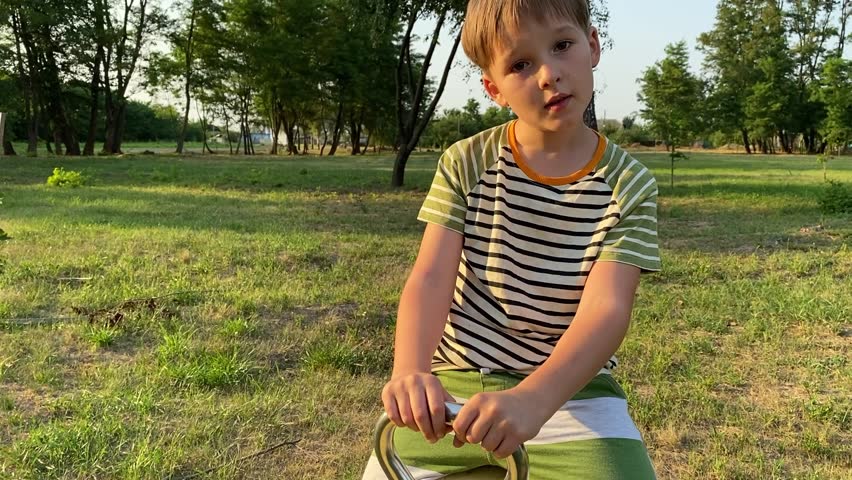 A young father enjoys quality time with two elementary aged children at outdoor playground on a warm summer day. The family engages in fun activities, laughter, play, the most of leisure time together