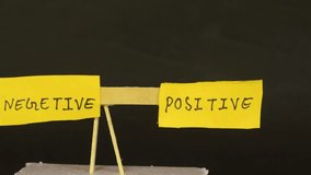 A handmade paper seesaw with handwritten sticky notes showing 'Positive' and 'Negative' sides, symbolizing balance and motivation, perfect for inspirational or educational themes. - Powered by Shutterstock - Get 15% off with code: PIKWIZARD15