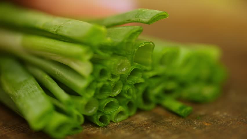 Slicing green onions macro close-up. Preparation of organic vegetable products for cooking. High quality 4k footage