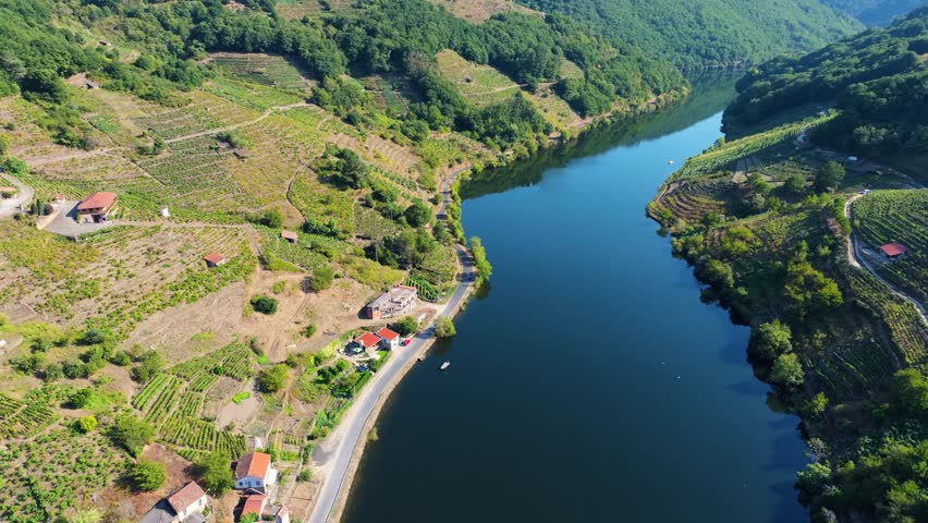 A drone scenic landscape view of Minho River surrounded by green mountains on a sunny day in Terra de Lemos, Lugo, Galicia, Spain