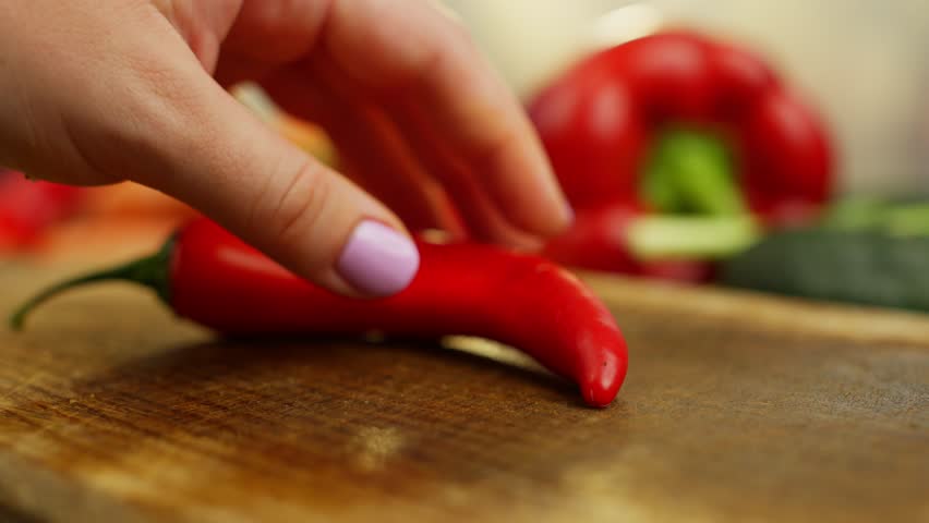 Slow-motion video of slicing hot chili peppers. Cooking with organic fresh spicy vegetables. High quality 4k footage