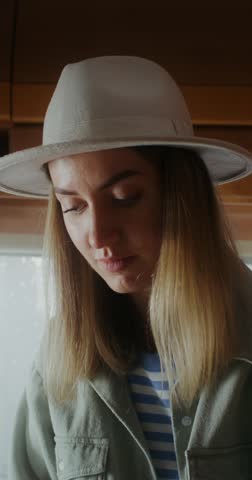 A young woman in a hat smiles as she finishes using a laptop while sitting on a bed in a van, she closes the laptop lid