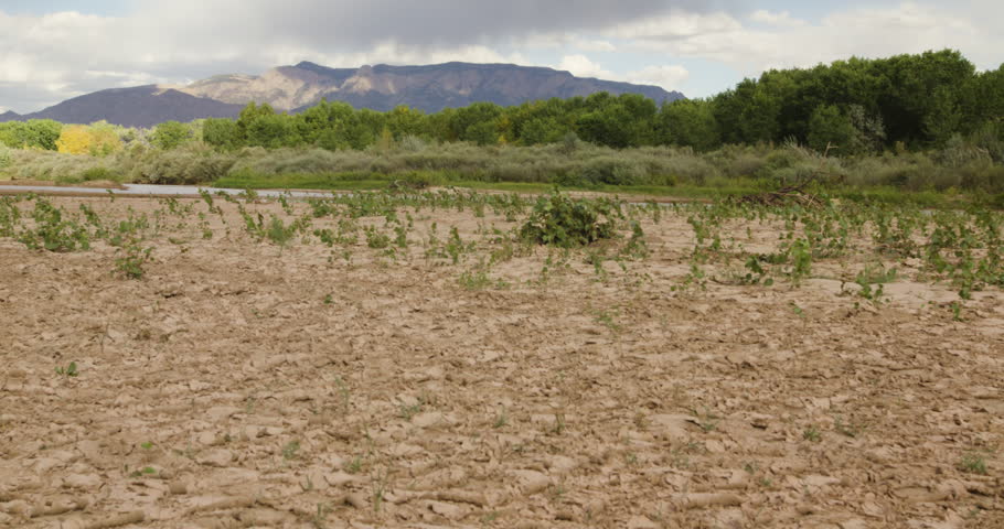 Steady shot of the Rio Grande drying out with Sandia Mountains in the back round.