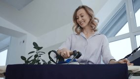 Smiling woman carefully irons a blue shirt on an ironing board. Enjoying her time, she engages in household chores, showcasing a cheerful and busy domestic lifestyle - Powered by Shutterstock - Get 15% off with code: PIKWIZARD15
