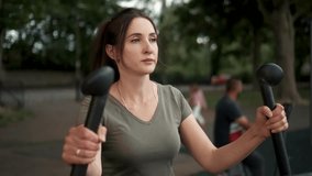 Woman exercising at outdoor gym. Intense workout for weight loss on elliptical. Woman Engaged in Workout Routine on Outdoor Fitness Equipment at Park During Late Afternoon - Powered by Shutterstock - Get 15% off with code: PIKWIZARD15