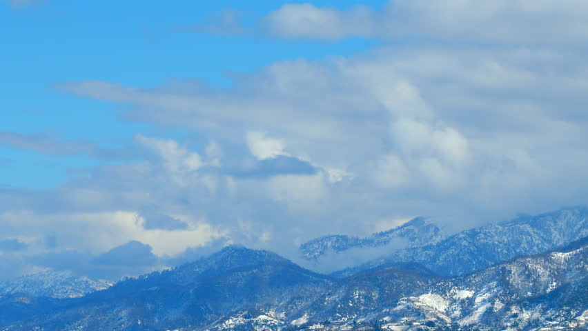 White Clouds Opposite Direction Glide Between Mountain Peaks. Iconic View Of Winter Wonderland Winter Background. Timelapse.
