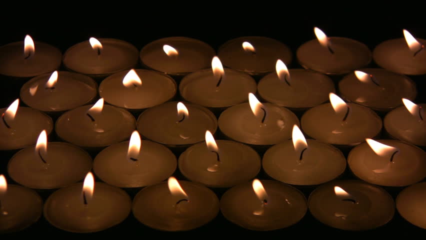 Flame (fire) of many candles vibrate on a wind. A black background