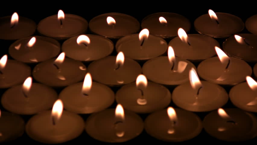 The flame of candles shivers on a wind. The candles blow and becomes darkly,