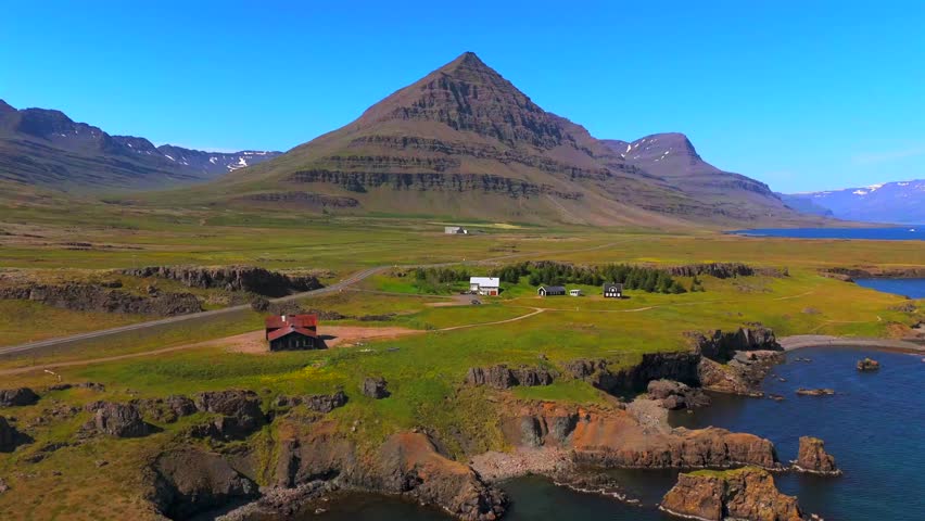 Explore the untouched wilderness of Iceland with a bird’s-eye view of Djúpivogur, where majestic mountains rise above crystal-clear waters.
