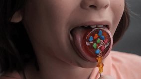 A girl licks a vibrant lollipop candy adorned with colorful hearts outside, An extreme closeup shot of a little girl savoring the homemade sweetness with her tongue. - Powered by Shutterstock - Get 15% off with code: PIKWIZARD15
