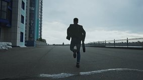 A man is sprinting along a deserted urban road, flanked by tall buildings, as dark clouds loom overhead. The atmosphere is tense, hinting at urgency or escape. - Powered by Shutterstock - Get 15% off with code: PIKWIZARD15
