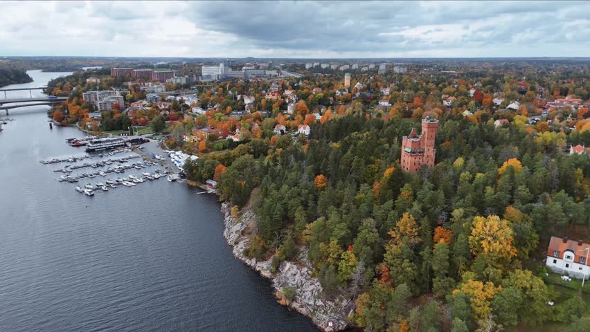 Brick castle on a cliff near water and forest during autumn.