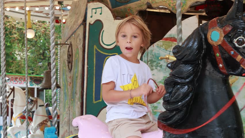 Child, going on Merry Go Round, kids play on carousel in the summer	
