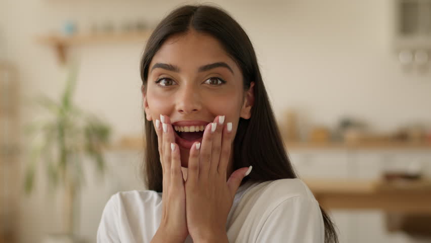 Portrait surprised amazed wondering Indian woman Arabian girl Latina female say wow open mouth big eyes reaction amazing good news achievement at home looking at camera happy excited face win success