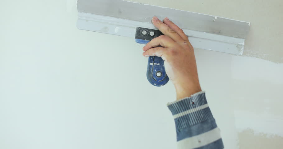 Plastering a concrete wall with putty using a large spatula. The master of apartment renovation levels the walls with starting plaster. The internal construction and finishing work.