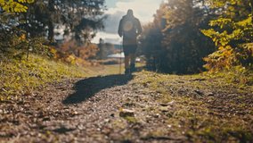 Close-up of a hiker's boots as they walk along a forest trail with trekking poles. The autumn foliage and sunlight create a peaceful nature atmosphere. Concept of outdoor hiking adventure. Slow motion - Powered by Shutterstock - Get 15% off with code: PIKWIZARD15