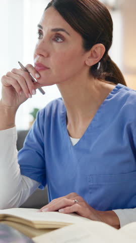 Nurse, woman and books with studying in home for medical research, nursing guide and diagnosis reference. Healthcare worker, person and writing in dining room for treatment plan review and knowledge