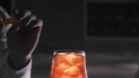 Bartender squeezes the orange peel out of the orange peel, which splashes onto the edges of a glass with a refreshing cool orange cocktail Aperol Spritz - Powered by Shutterstock - Get 15% off with code: PIKWIZARD15