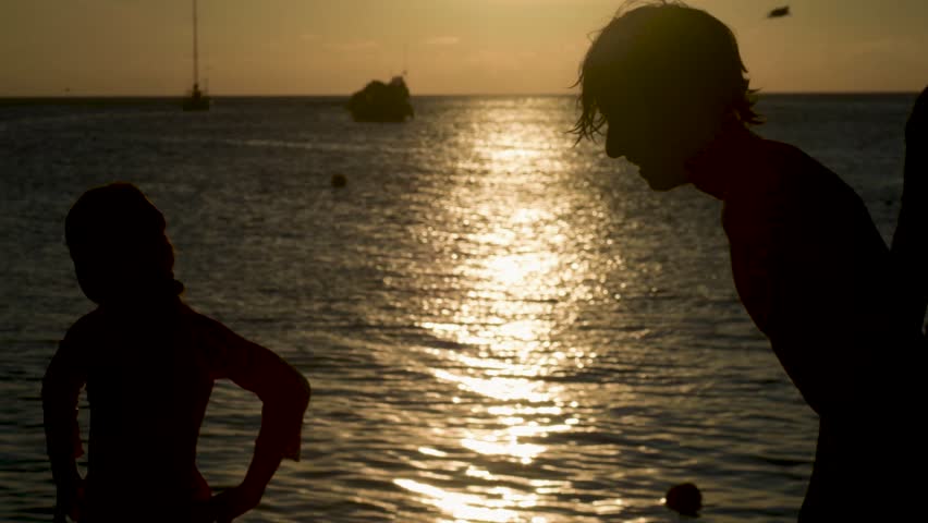 A group of friends on pier cool off by jumping and throwing themselves. Sunset, Los Roques Venezuela