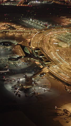 Aerial nighttime shot of bustling activity at a busy airport runway and terminal complex